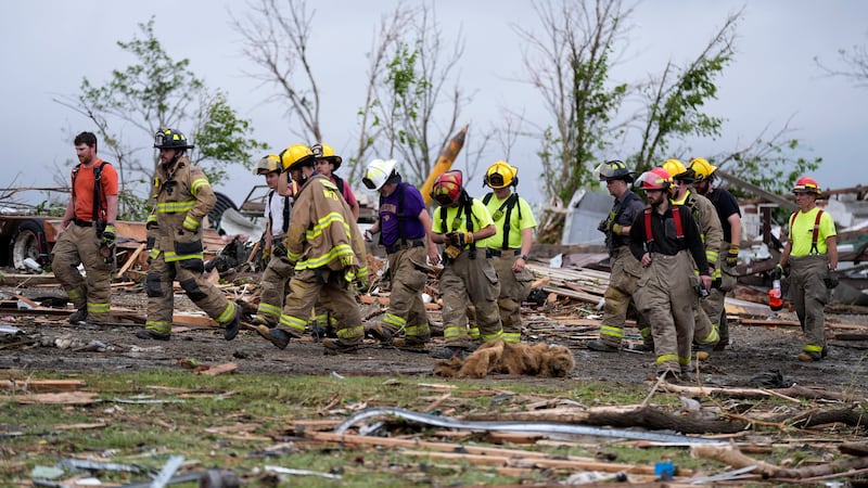 Firefighters walks among tornado-damaged homes, Tuesday, May 21, 2024, in Greenfield, Iowa....