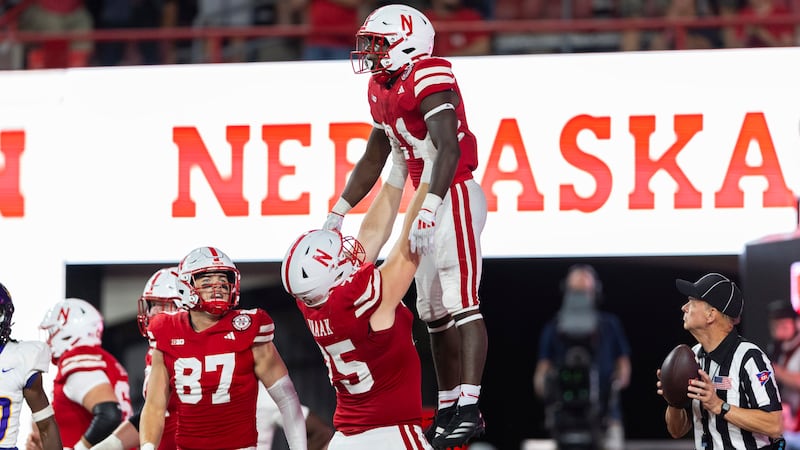 Nebraska's Tyler Knaak, center, lifts Emmett Johnson, right, in celebration of Johnson's...